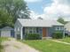 Charming single-story home with blue siding, mature landscaping, and detached garage at , Indianapolis, IN 46218