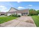Well-maintained brick home with a green lawn, garages, and a charming front porch at 1905 Persimmon Grove Dr, Indianapolis, IN 46234