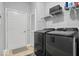 A modern laundry room with gray machines, white cabinets above, and a door to the backyard for easy access at 1905 Persimmon Grove Dr, Indianapolis, IN 46234