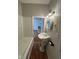 A classic bathroom with a pedestal sink, white bath and new light fixture is situated off a doorway to the kitchen at 1920 Kildare Ave, Indianapolis, IN 46218