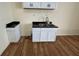 Kitchen area has white cabinets, stainless steel sink, black countertops and wood patterned flooring at 1920 Kildare Ave, Indianapolis, IN 46218