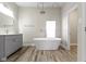 Bright bathroom featuring a standalone tub, gray vanity, modern fixtures, and stylish wood-look floors at 2111 S A St, Elwood, IN 46036
