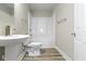 Well-lit bathroom showcasing a sleek pedestal sink, toilet, and convenient shower-tub, complete with essential fixtures at 2111 S A St, Elwood, IN 46036
