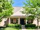 Inviting brick home with a covered front porch, white columns and mature trees at 2223 Shaftesbury Rd, Carmel, IN 46032