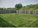 Wide shot of the fenced backyard showing lush grass and a small fire pit at 2432 Bridlewood Dr, Franklin, IN 46131