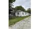 Exterior of a white single-story home with a red front door, weathered siding, and a gravel driveway at 2627 Lincoln St, Anderson, IN 46016