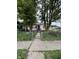 View of a white single-story home with a red door and trees in the front yard, behind a chain link fence at 2627 Lincoln St, Anderson, IN 46016