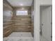 Beautifully tiled walk-in shower featuring a shower head, niche, and window for natural light at 2903 Winthrop Ave, Indianapolis, IN 46205