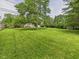 Lush backyard featuring a sprawling lawn, mature trees, a wooden deck, and a storage shed, offering ample outdoor space at 3004 N Timber Ln, Muncie, IN 47304