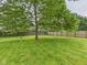 Spacious backyard with lush green grass, mature trees, and a birdbath, perfect for outdoor activities and relaxation at 3004 N Timber Ln, Muncie, IN 47304