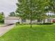 Ranch-style home with attached garage, well-manicured lawn, and garden beds full of colorful flowers at 3004 N Timber Ln, Muncie, IN 47304
