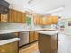 View of the kitchen featuring light wood cabinets, laminate countertops, stainless dishwasher, and a kitchen island at 3004 N Timber Ln, Muncie, IN 47304