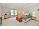 Relaxing bedroom with soft gray walls, tray ceiling, wood chest, and sitting area by a bright window at 3872 New Battle Ln, Bargersville, IN 46106