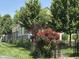 Yellow home surrounded by a black fence, lush trees, green grass, and a rose bush at 407 N Alton Ave, Indianapolis, IN 46222