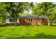 Backyard featuring a brick house with a patio, table, chairs and green lawn at 4275 Springwood Trl, Indianapolis, IN 46228