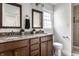 Bathroom featuring dual sinks, framed mirrors, granite countertops, and a tiled shower at 4275 Springwood Trl, Indianapolis, IN 46228