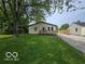 Single-story house featuring a front porch, green lawn, and a gravel driveway at 450 N Fenton Ave, Indianapolis, IN 46219