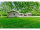 Spacious backyard features a well-maintained lawn, mature trees, and an attached garage with wood storage at 4853 E 65Th St, Indianapolis, IN 46220
