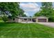 Expansive backyard showcasing a patio, attached garage, well-kept lawn, and mature trees for privacy at 4853 E 65Th St, Indianapolis, IN 46220