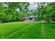 Well-manicured front yard featuring a charming single-story home with mature trees, creating a picturesque setting at 4853 E 65Th St, Indianapolis, IN 46220