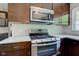 Close-up of a modern stainless steel stove and microwave with dark wood cabinets and white countertops at 4853 E 65Th St, Indianapolis, IN 46220