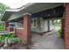 A covered porch with brick pillars and green siding leads to the entrance of the home at 5133 E Michigan St, Indianapolis, IN 46219