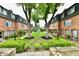 Beautifully landscaped lawn and mature trees enhance the curb appeal of the brick townhome complex at 5153 Brendonshire Ct, Indianapolis, IN 46226