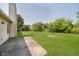 An expansive, manicured backyard bordered by mature trees and a paved walkway near the house at 7418 Southern Lakes Dr, Indianapolis, IN 46237