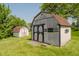 A well-maintained storage shed with a roof and double doors stands in a large backyard at 7418 Southern Lakes Dr, Indianapolis, IN 46237