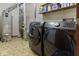 A functional laundry room with a washer, dryer, water heater, and storage shelves at 7426 Shadow Wood Dr, Indianapolis, IN 46254