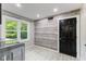 Functional laundry room with shiplap wall, window view and a black painted door at 7630 Blain Way, Indianapolis, IN 46254