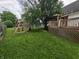 Expansive backyard featuring a deck, playset, mature trees and lush green lawn at 802 Fern Dr, Shelbyville, IN 46176