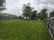 Large grassy backyard with a wooden playset and a trampoline at 802 Fern Dr, Shelbyville, IN 46176