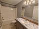 A bright bathroom includes a tub-shower combo, toilet, and marble-look vanity with sink at 802 Fern Dr, Shelbyville, IN 46176