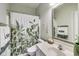 Bathroom featuring a shower with green leafy patterned curtain, sink, toilet, and decorative wall hangings at 9698 Coyote Ct, Noblesville, IN 46060