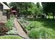 Landscaped backyard featuring a raised garden bed, manicured lawn, and mature trees at 1065 Lakewood South Dr, Brownsburg, IN 46112