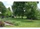 Lush backyard featuring a raised garden bed, beautiful green lawn, and mature trees providing shade at 1065 Lakewood South Dr, Brownsburg, IN 46112
