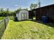 View of shed and covered patio in well-maintained backyard with lawn and black chain link fence at 10725 Tedder Lake Dr, Indianapolis, IN 46239