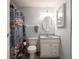 Bathroom with colorful shower curtain, white vanity, toilet, fixtures and white woven mirror at 1325 Countryside Ln, Indianapolis, IN 46231
