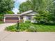 Charming home featuring a well-manicured front lawn, colorful flowers, and a large, two car garage at 1325 Countryside Ln, Indianapolis, IN 46231