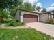 Two car garage featuring a paved driveway and lush green lawn and garden in front of the house at 1325 Countryside Ln, Indianapolis, IN 46231