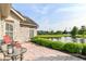 Relaxing outdoor patio with pond view, stone pavers, with decorative bushes and a black metal table at 13807 Rue Fontaine Ln, McCordsville, IN 46055