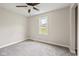 Bright bedroom with plush gray carpet, a ceiling fan, and a large window with a green outdoor view at 1382 S Morgantown Rd, Greenwood, IN 46143