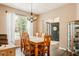 Bright dining room with wooden table and chairs, chandelier, and view of the front yard through large windows at 13861 Barberry Ct, Carmel, IN 46033