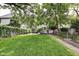 A beautifully landscaped backyard with lush green grass, mature trees, a patio, and a charming garden area at 1548 N Park Ave, Indianapolis, IN 46202