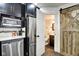 A view of the kitchen, an open bathroom with a toilet, vanity, sink, mirror, and a rustic wooden barn door at 1548 N Park Ave, Indianapolis, IN 46202
