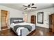 Bedroom with ensuite bathroom, hardwood floors, ceiling fan, closet, and dark mirror at 1548 N Park Ave, Indianapolis, IN 46202