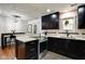 Open-concept kitchen with black cabinets, modern appliances, and breakfast bar leading to dining area at 1548 N Park Ave, Indianapolis, IN 46202