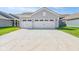 Home's three-car garage featuring a large concrete driveway and manicured lawn at 1694 Windrush Pl, Westfield, IN 46074