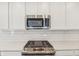 Close up of stainless steel microwave and range top, with subway tile backsplash and shaker cabinets at 1694 Windrush Pl, Westfield, IN 46074